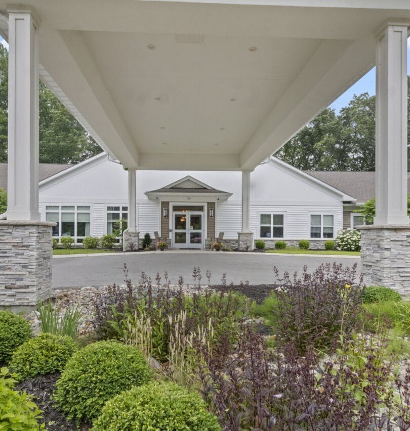 Exterior view of Lakeshore Woods Seniors community entrance with landscaped garden and covered driveway.